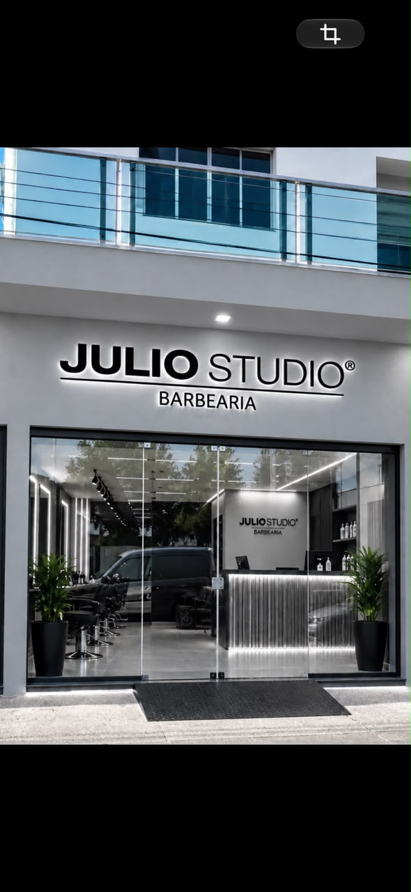 Fachada do Júlio Studio, com letreiro e interior da barbearia em tons de cinza